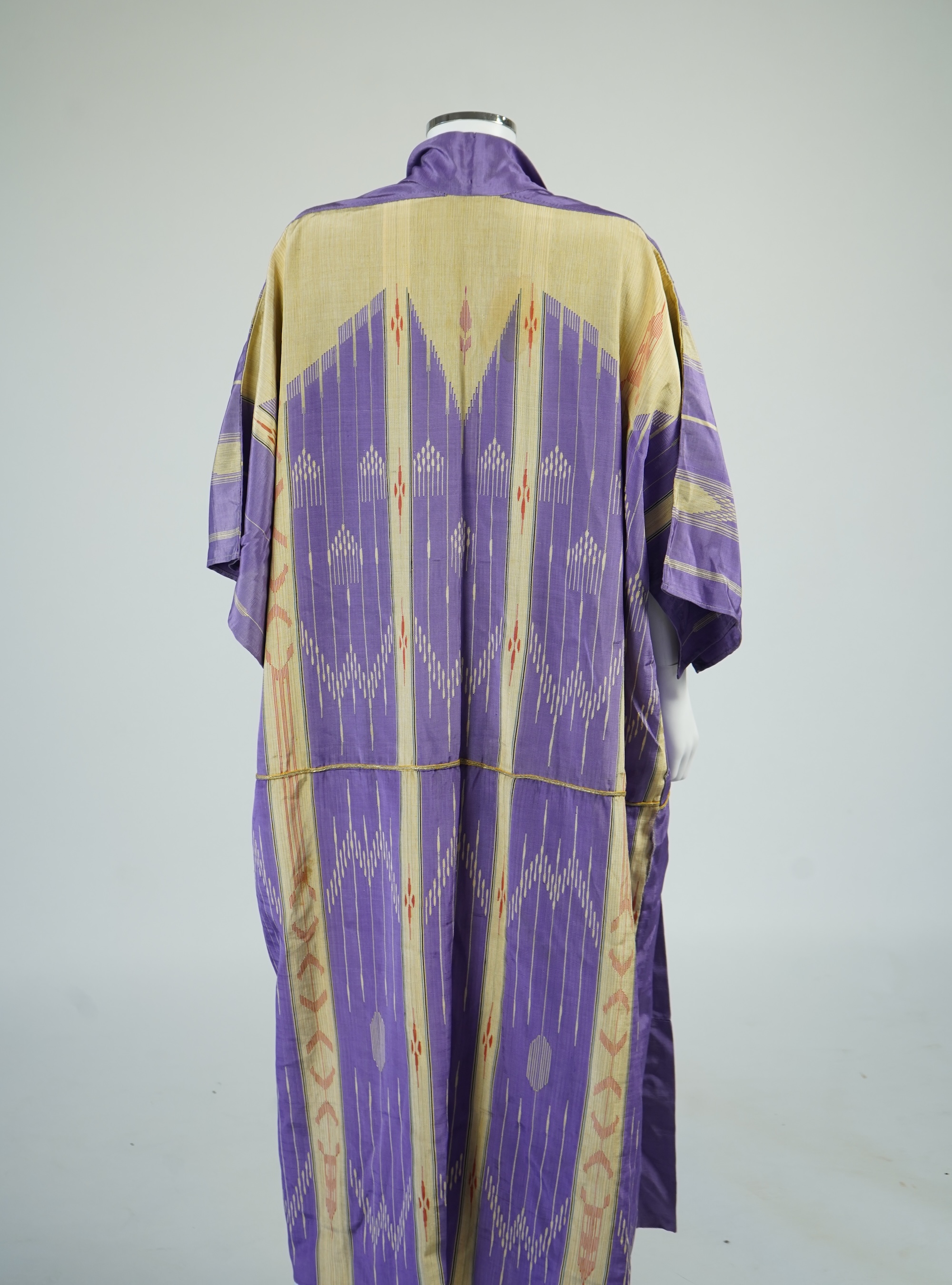 An early 20th century Syrian hand woven silk coat. Woven with stripes and geometric shapes in purple and yellow and red., 130 cm long. Condition - good, colours and fabric strong.